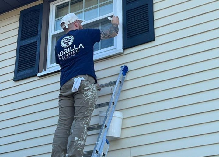 painter on a ladder painting the exterior window trim
